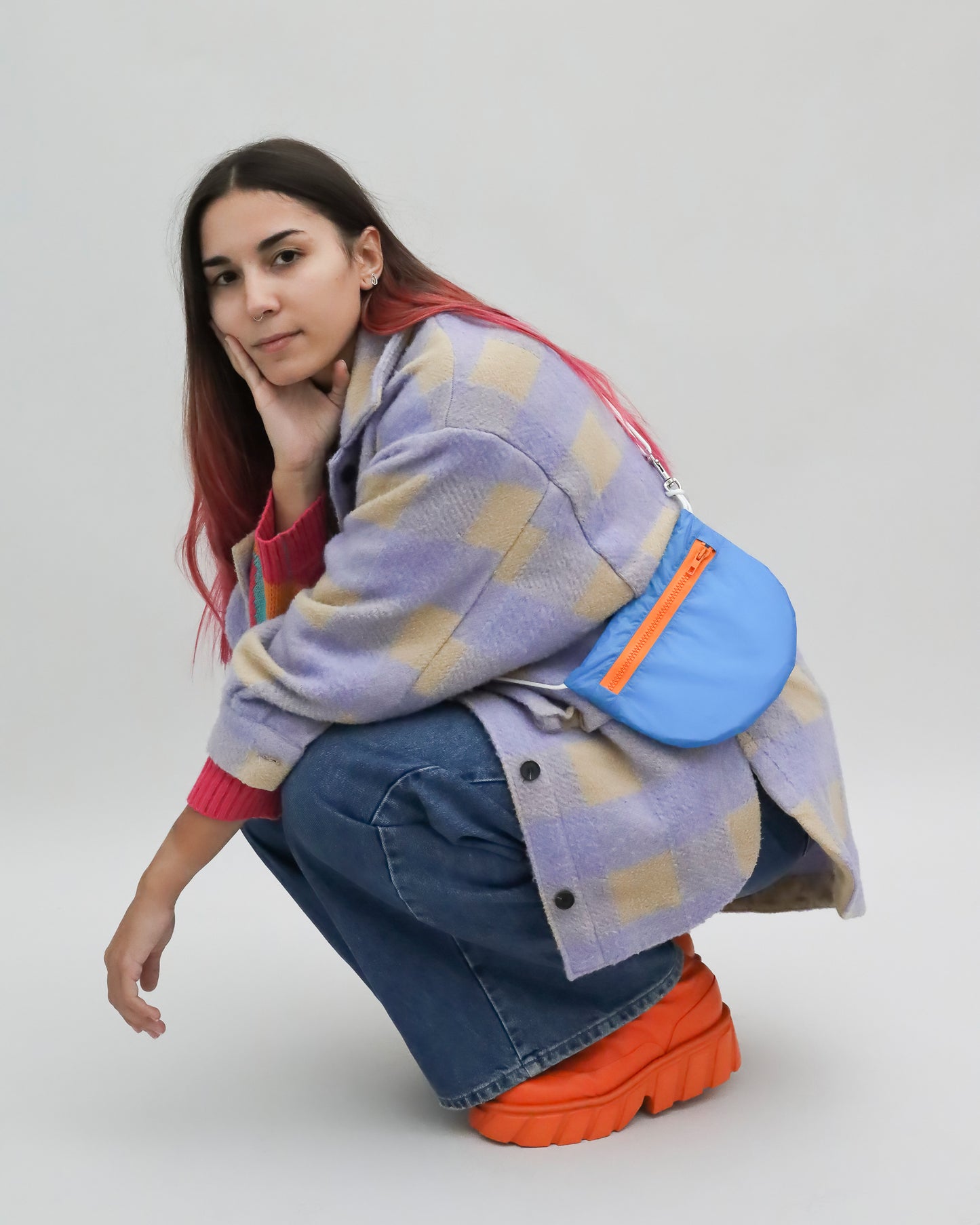 Model wears royal blue and orange crossbody bag made from vintage paragliders U.BAG
