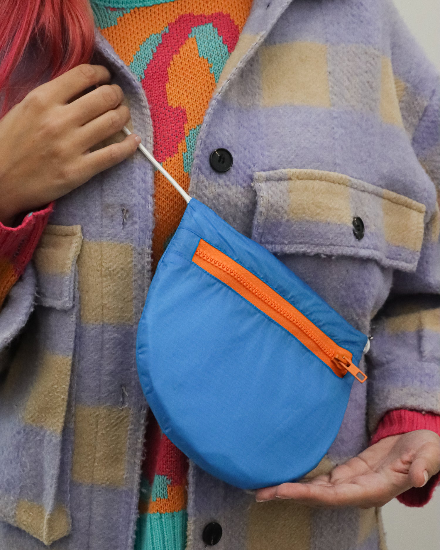 Model wears royal blue and orange crossbody bag made from vintage paragliders U.BAG