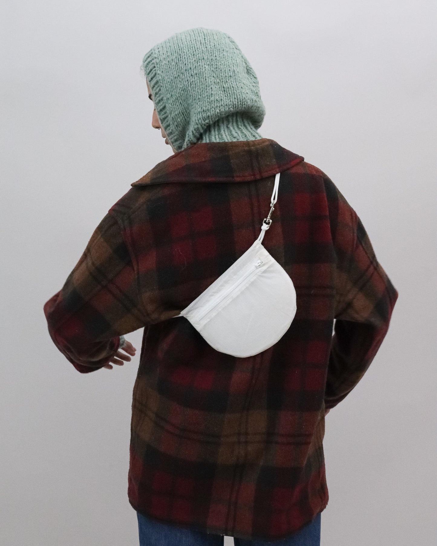 Model wears Cross body bag in white / clear from upcycled nylon cut from vintage paragliders