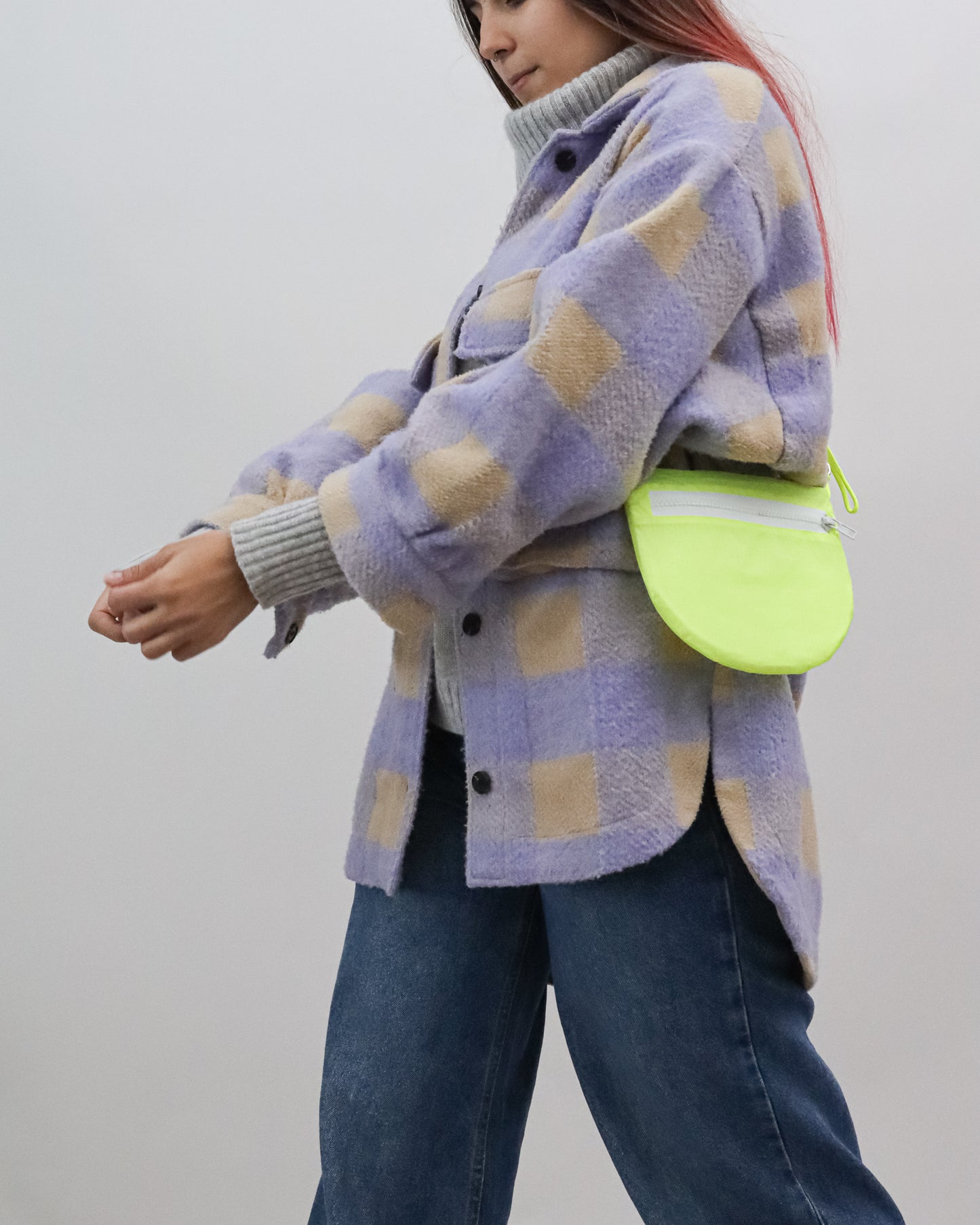Model wearing sling bag in neon yellow and white made from a vintage paraglider