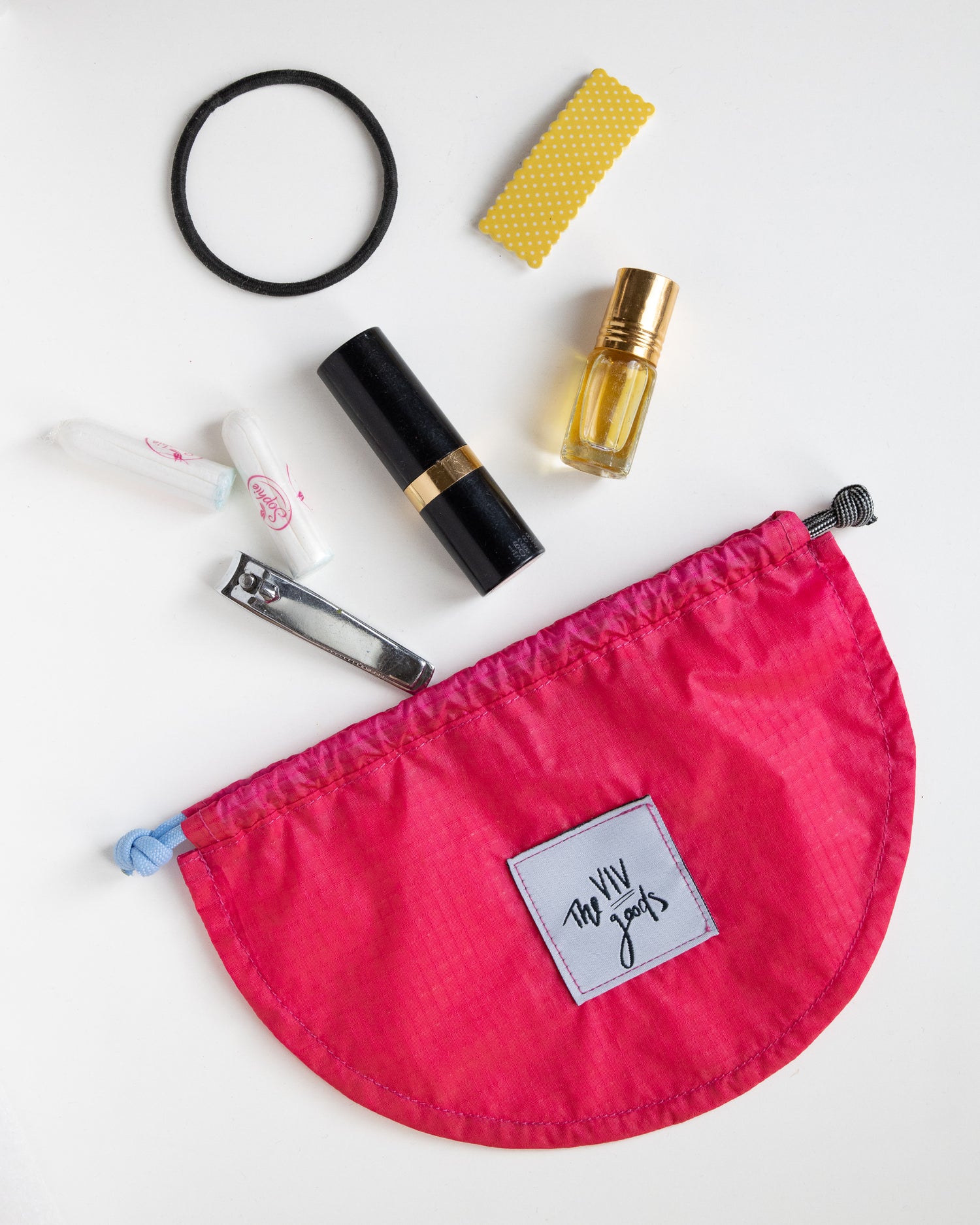 flat lay of drawstring pouch in hot pink, light blue and grey with accessories that can fit inside bag