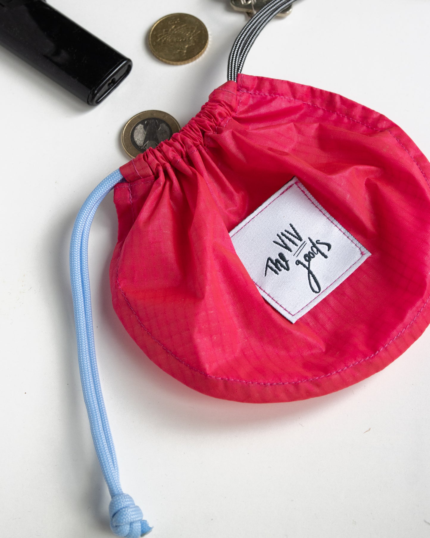 flat lay of drawstring pouch in hot pink, light blue and grey with bag closed