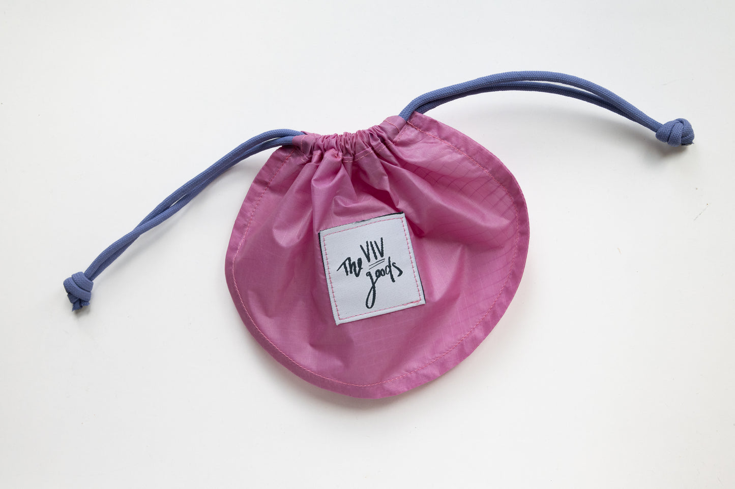 flat lay of drawstring pouch in hot pink, light blue and grey with bag closed