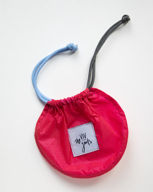 flat lay of drawstring pouch in hot pink, light blue and grey with bag closed