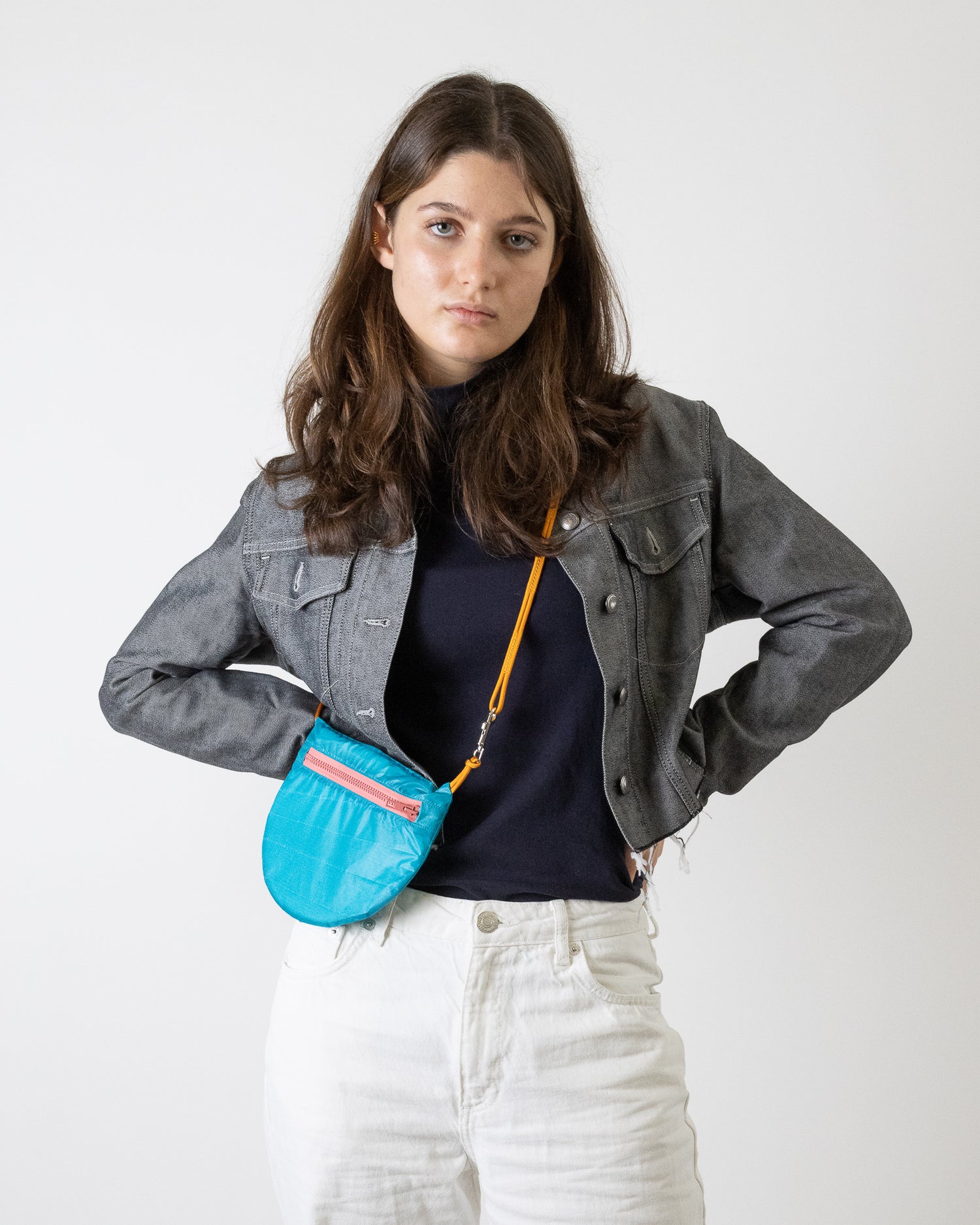 Model wears teal sling bag with dusty rose zipper made from upcycled paraglider nylon U.BAG