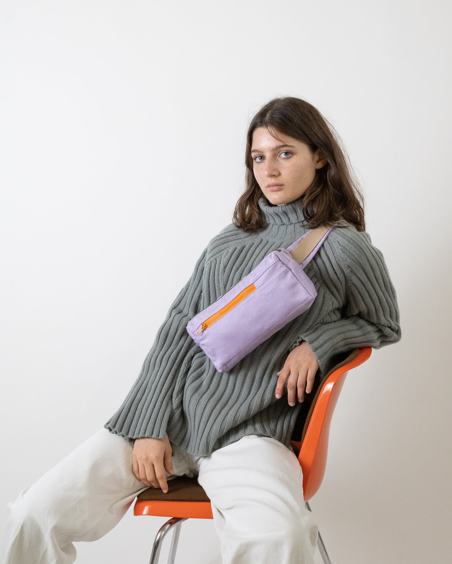 model wearing lavender fanny pack bag with orange zipper made from reclaimed canvas