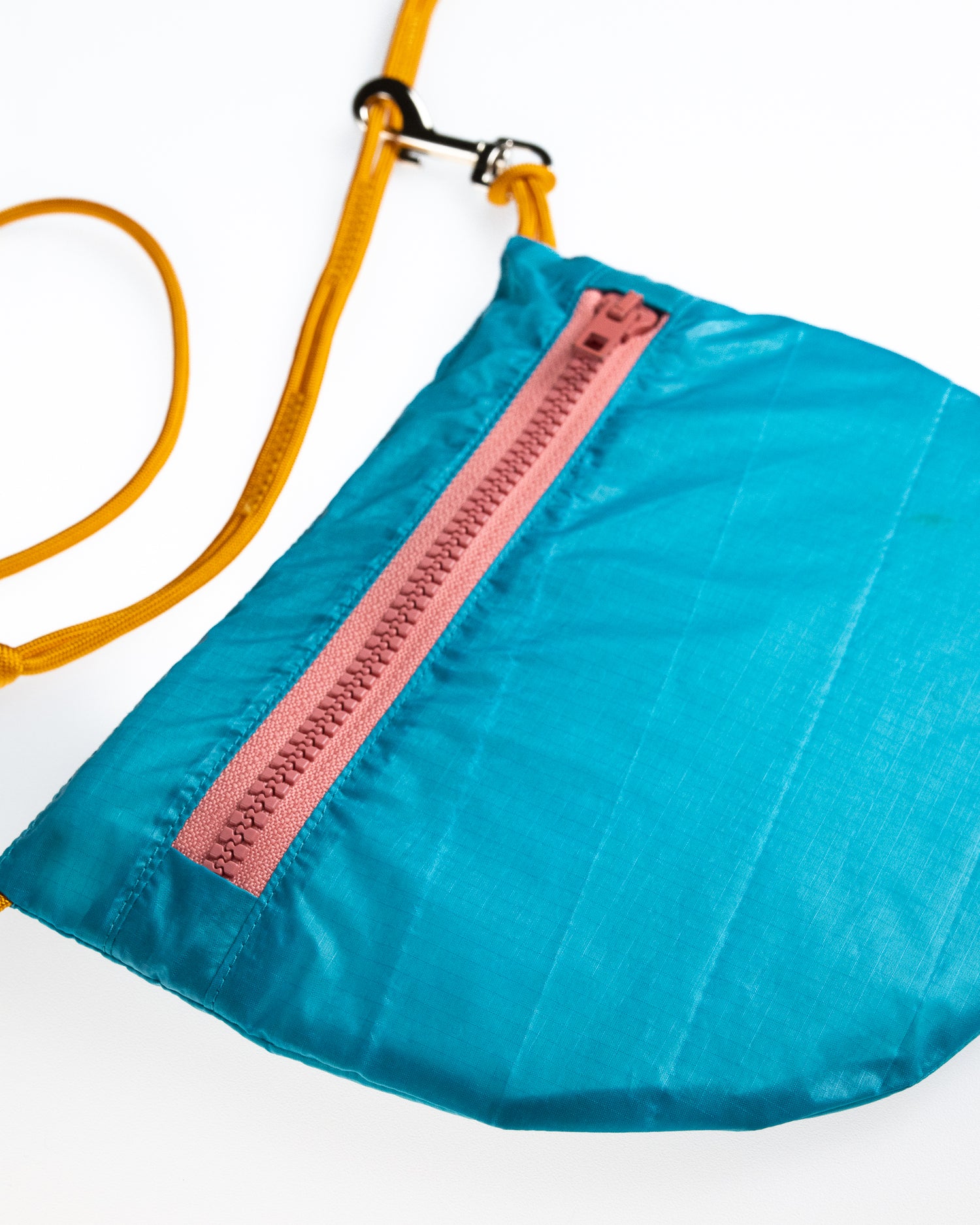 sling bag in turquoise with dusty rose zipper and orange rope strap made from recycled ripstop nylon