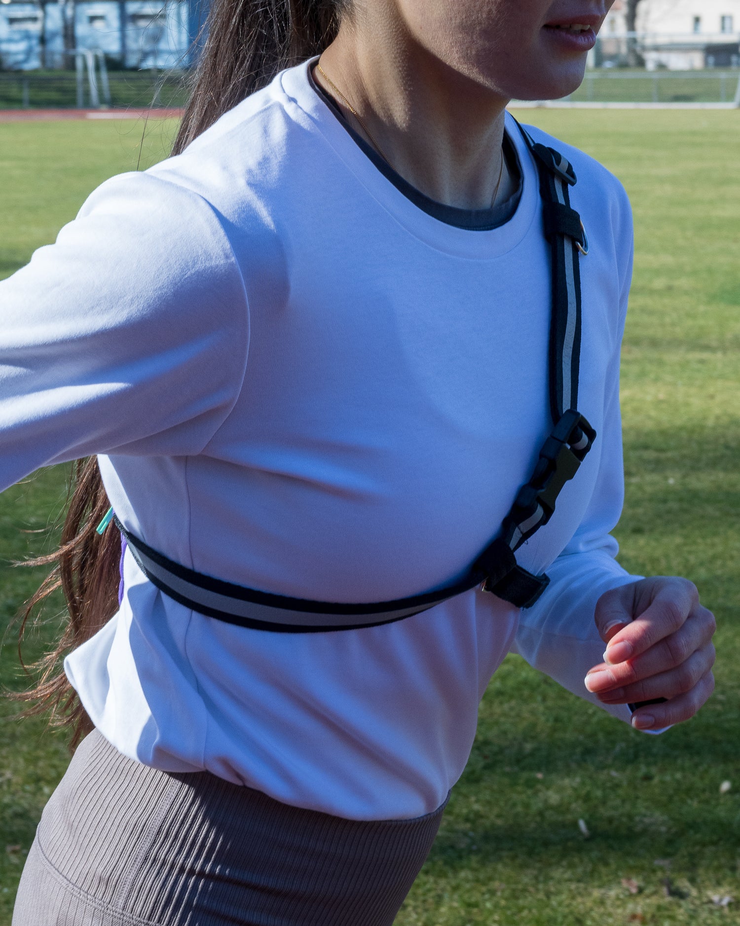 Runner wearing the SPORT.BAG with the reflective T-strap securely velcroed to her chest.