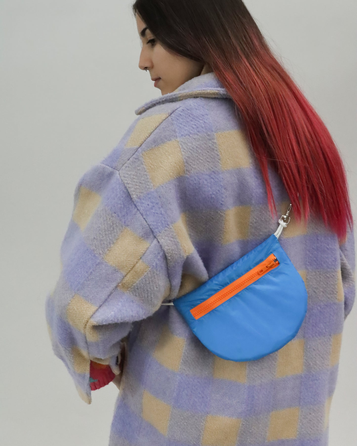 Model wears royal blue and orange sling bag made from vintage paragliders U.BAG